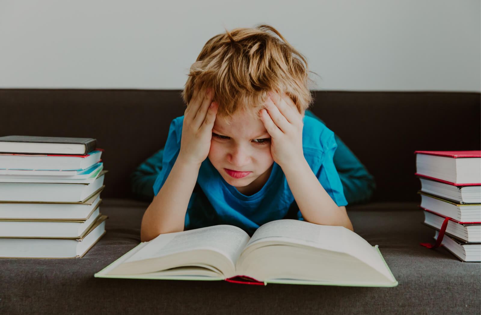 A young boy looking stressed as he tries to read a book.
