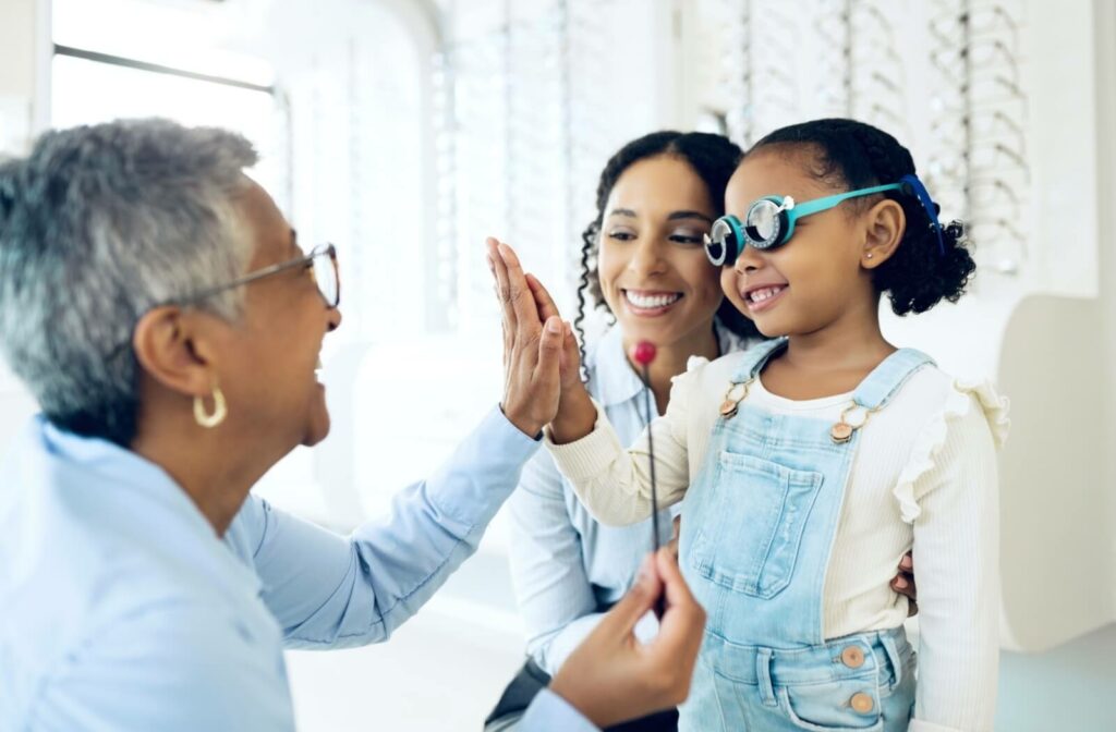 A child and their optometrist high-five after a comprehensive eye exam.