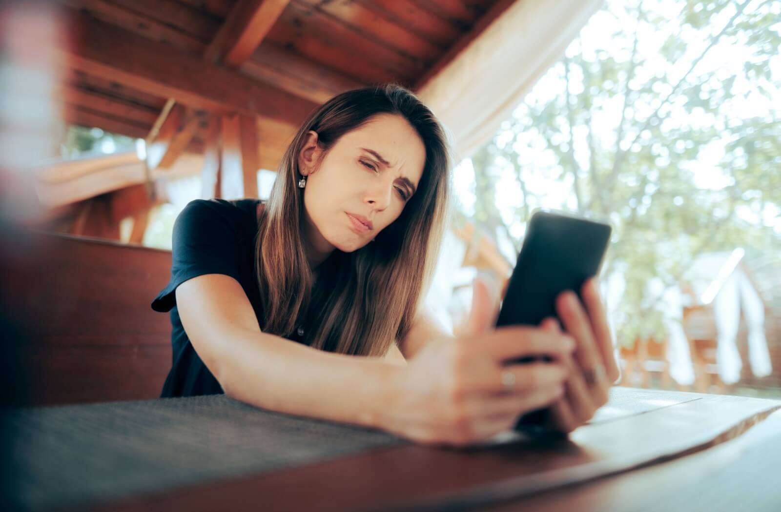 A person squinting and looking confused while viewing a smartphone screen.