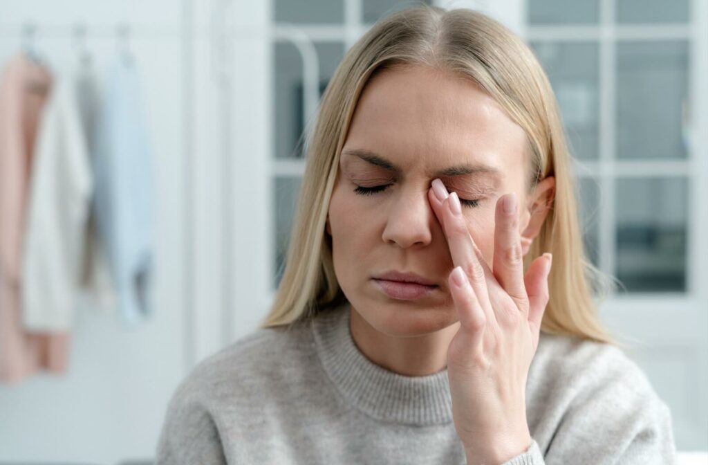 An individual with closed eyes rubbing their eyelid to relieve dryness or irritation.